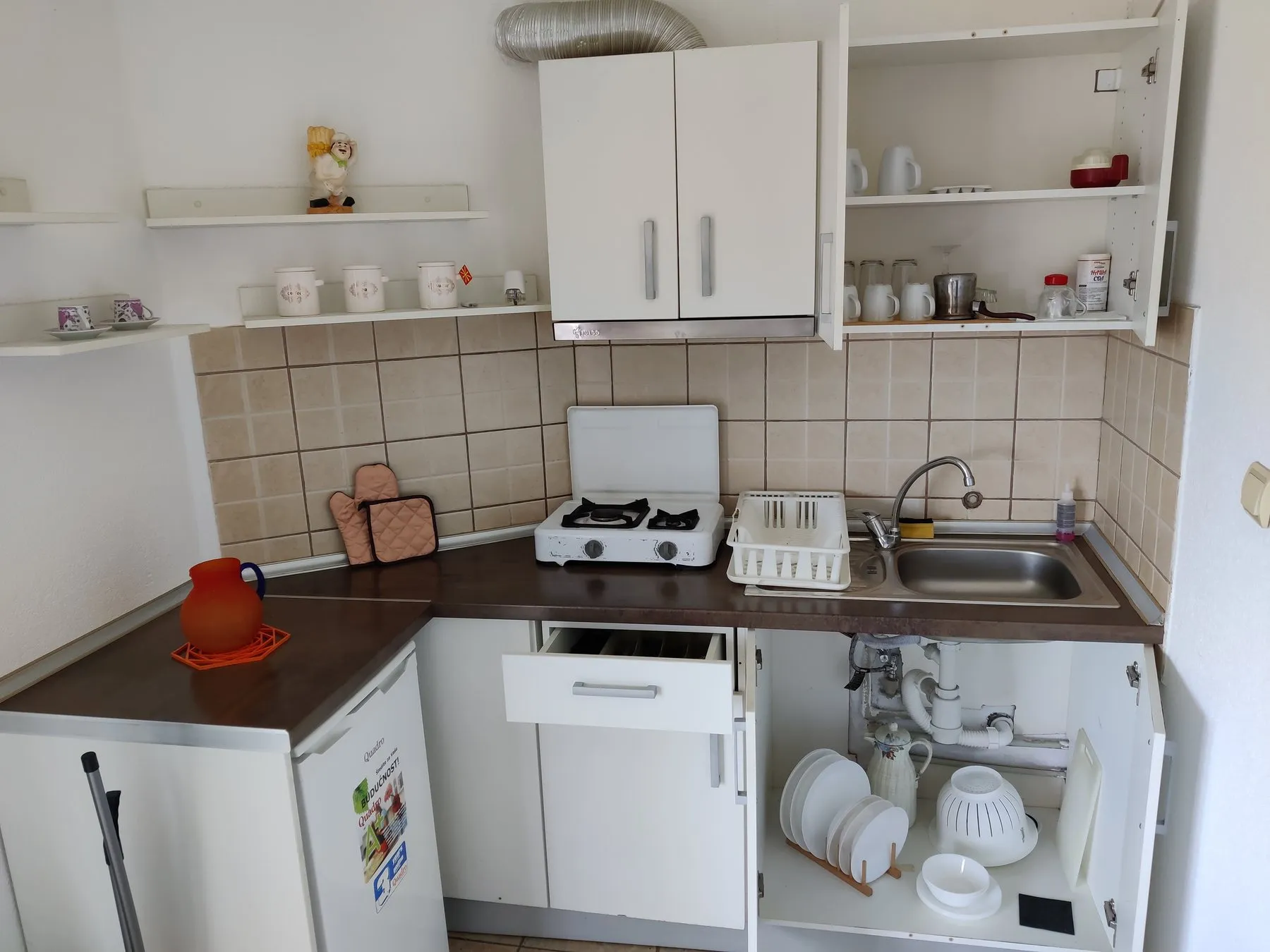 Kitchenette with cooker, sink, storage, and dishware