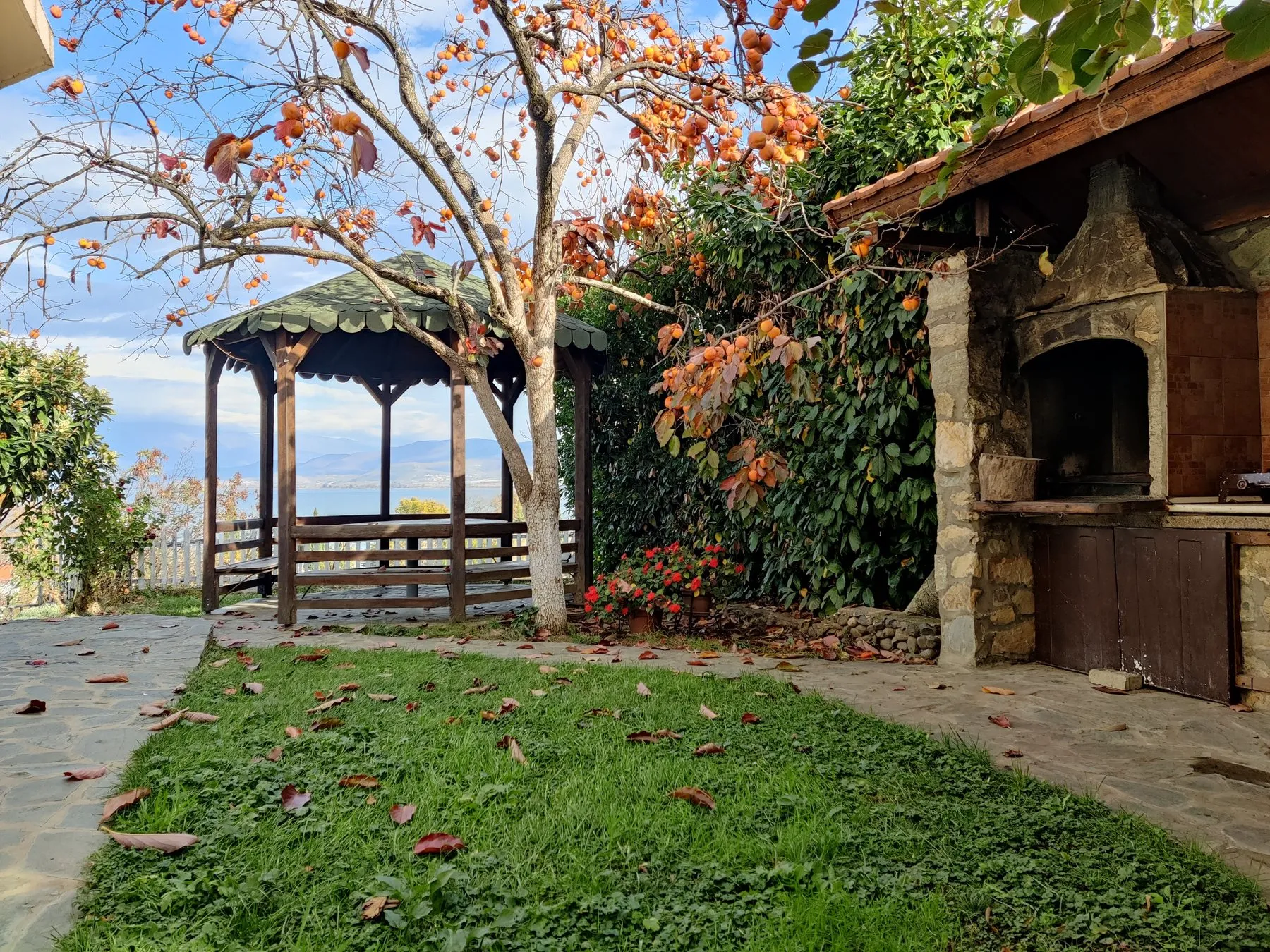 Vila Roza garden with a pergola, flowers, stone paths, and Lake Dojran beyond